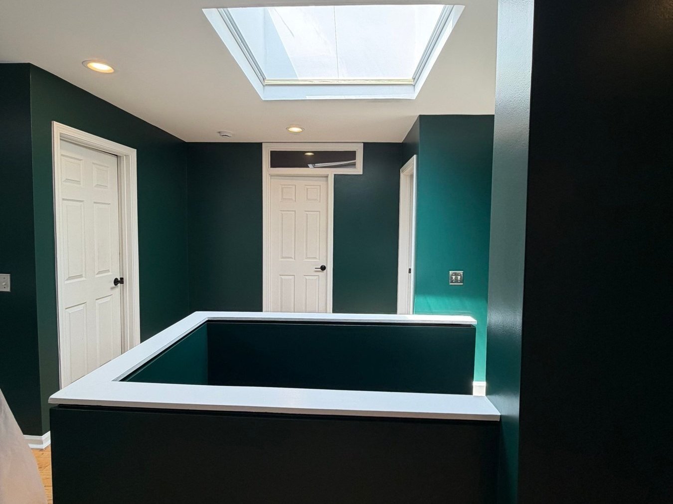 Stair landing painted deep green with white railing and trim